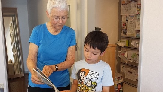 Grandmother showing a boy somethin in a magazine